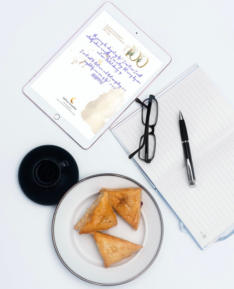 May include: An overhead shot of a workspace with a tablet displaying text, a notebook, glasses, a pen, a cup of coffee, and a plate with three pastries. The tablet has the text "The journey has changed my life! I can't wait... GRATEFUL!"
