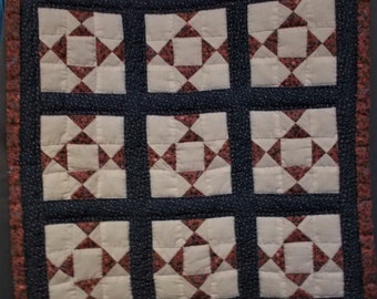 Puede incluir: Una colcha con un patrón repetitivo de cuadrados rojos, blancos y azules. La colcha está hecha de tela con un pequeño estampado floral.