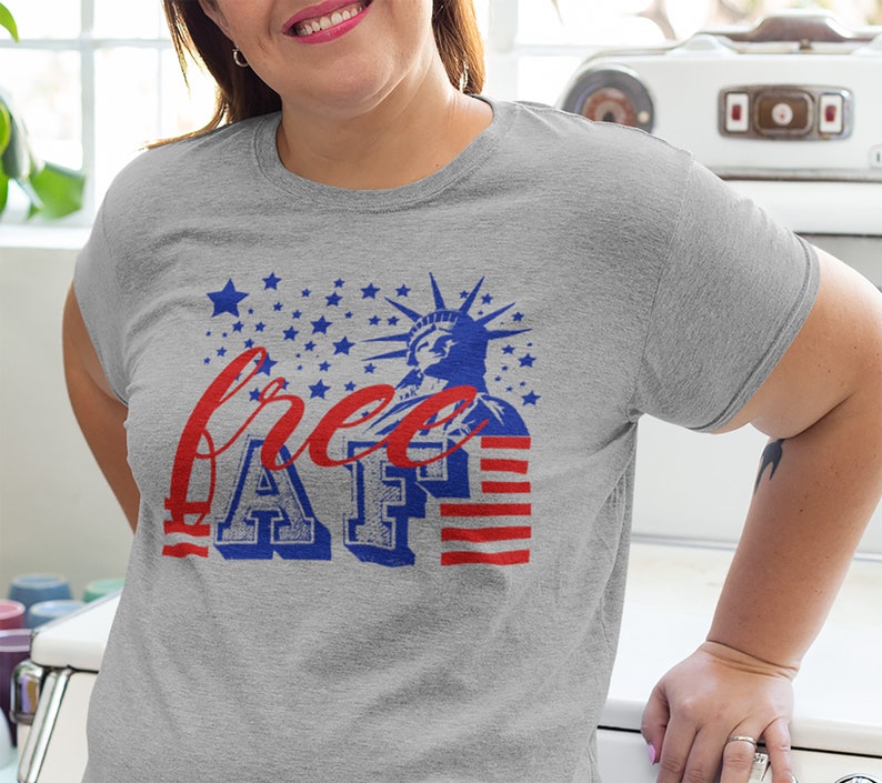 Peut inclure: T-shirt gris avec un motif graphique rouge, blanc et bleu repr&eacute;sentant la Statue de la Libert&eacute; et le texte "free AF".