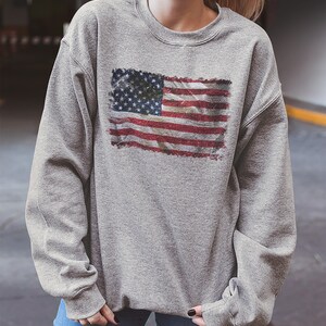 May include: A gray sweatshirt with a distressed American flag print.