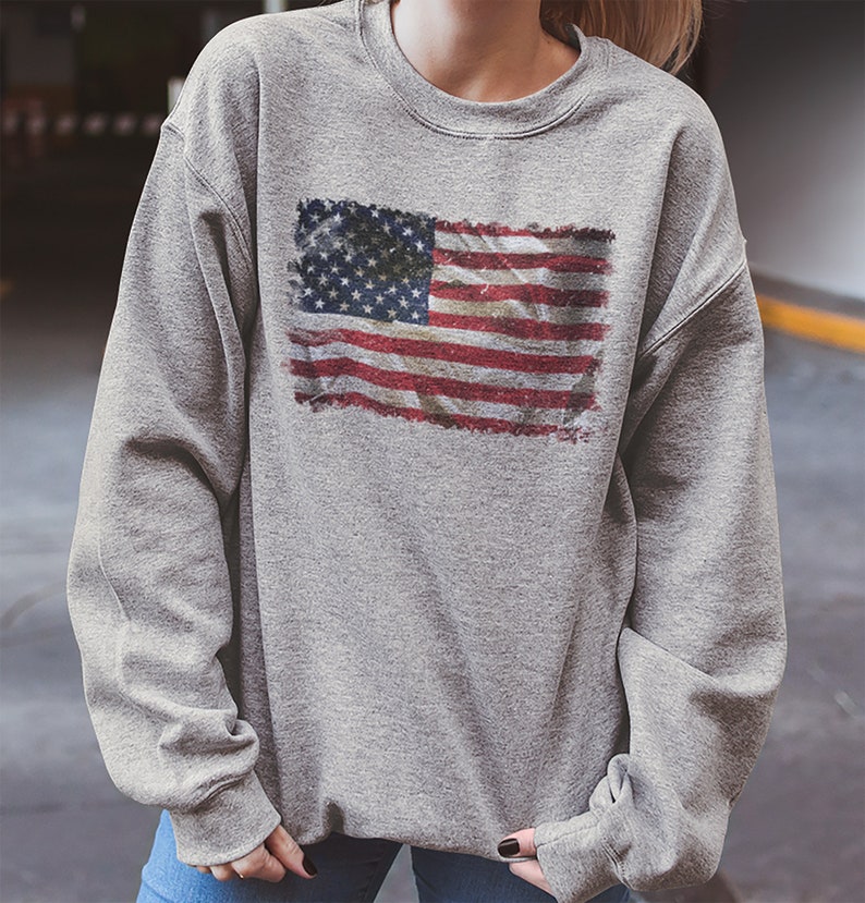 May include: A gray sweatshirt with a distressed American flag print.