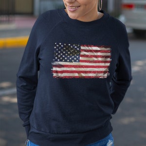 May include: A navy blue sweatshirt with a distressed American flag design printed on the front.