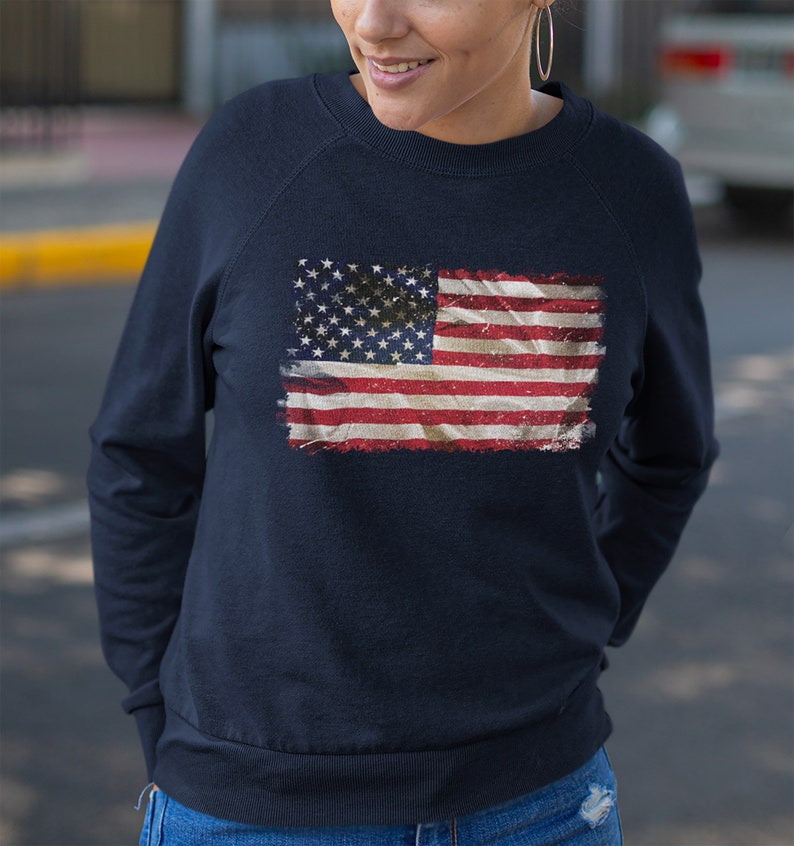 May include: A navy blue sweatshirt with a distressed American flag design printed on the front.