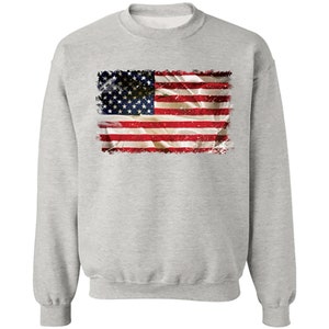 May include: A gray sweatshirt with a distressed American flag design printed on the front.