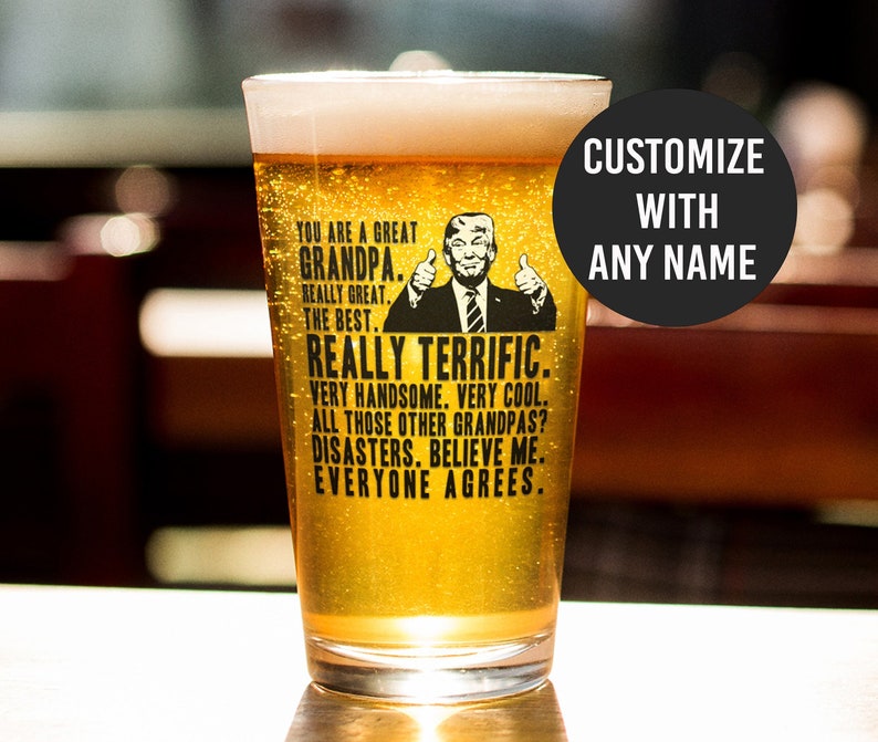 May include: A clear glass beer mug with a black and white graphic of a man with a thumbs up gesture. The text on the mug reads "You are a great Grandpa. Really great. The best. Really terrific. Very handsome. Very cool. All those other Grandpas? Disasters. Believe me. Everyone agrees."