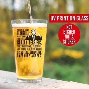 May include: A clear glass beer stein with a black and white image of a man with a thumbs up. The text on the stein reads "You are a great plumber. Really great. The best. Really terrific. Very handsome. Very cool. All those other plumbers? Disasters. Believe me. Everyone agrees."