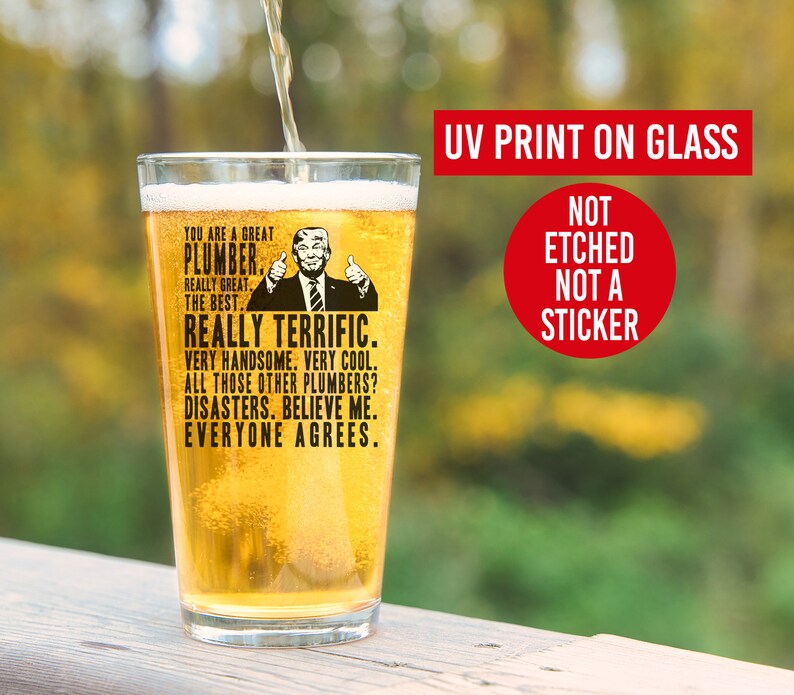 May include: A clear glass beer stein with a black and white image of a man with a thumbs up. The text on the stein reads "You are a great plumber. Really great. The best. Really terrific. Very handsome. Very cool. All those other plumbers? Disasters. Believe me. Everyone agrees."