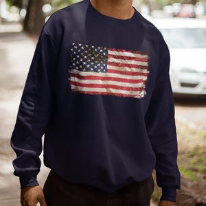 May include: A navy blue sweatshirt with a distressed American flag design printed on the front.