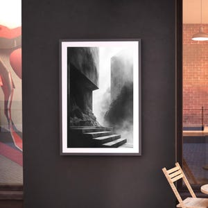 Puede incluir: Una impresi&oacute;n en blanco y negro enmarcada que representa una escena arquitect&oacute;nica misteriosa. La obra de arte presenta una escalera que conduce hacia arriba, flanqueada por estructuras imponentes y envuelta en niebla. La paleta monocrom&aacute;tica realza la atm&oacute;sfera dram&aacute;tica.