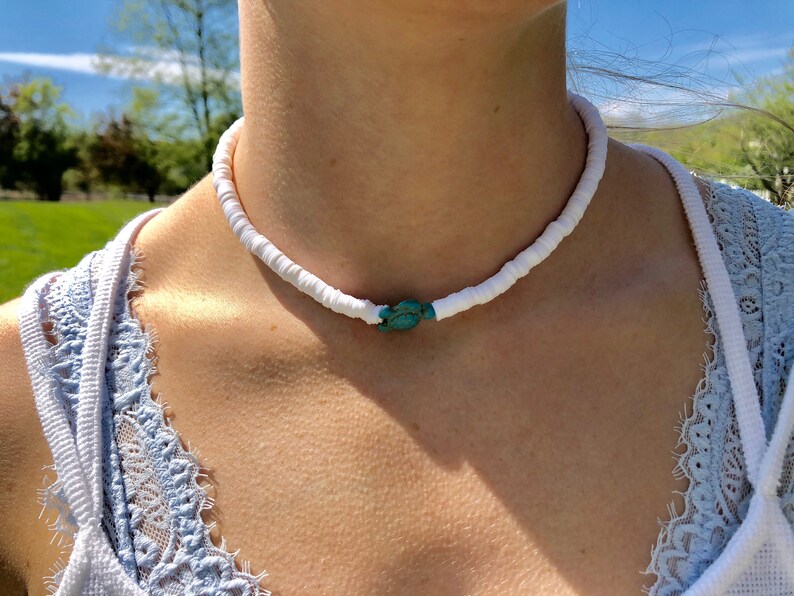 May include: A white shell choker necklace with a turquoise stone accent.
