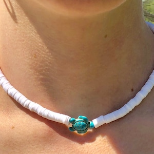 May include: A white shell necklace with a turquoise turtle charm.