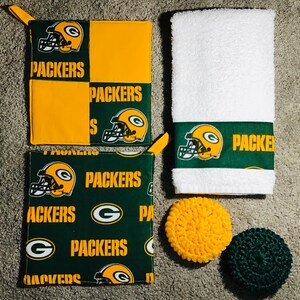 May include: Set of three green and yellow kitchen pot holders with a football helmet design and the word "Packers" printed on them. The pot holders are on a white background.