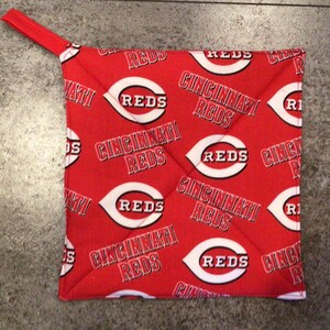 May include: Red and white pot holder with the Cincinnati Reds logo repeated on a red background.