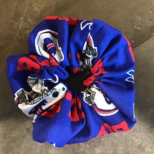May include: Blue and red fabric scrunchie with a white and gray pattern of football helmets and the word "Giants".