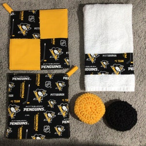 May include: Two black and yellow pot holders with the Pittsburgh Penguins logo, a white towel with a black and yellow band with the Pittsburgh Penguins logo, a yellow crocheted scrubby and a black crocheted scrubby.