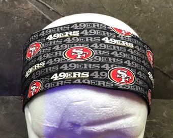 Puede incluir: Diadema negra y roja con el texto repetido "49ers" y el logotipo de los San Francisco 49ers.