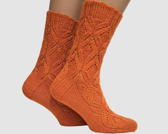 May include: A pair of orange knitted socks with a lacy pattern. The socks are shown on a model's legs.