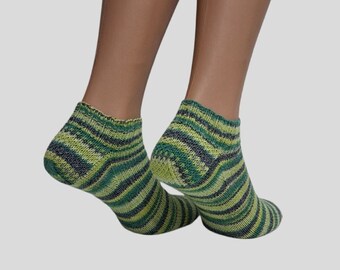 May include: A pair of ankle socks with a striped pattern in shades of green, yellow, and gray. The socks are made of a knitted material and have a ribbed cuff. The socks are displayed on a mannequin.