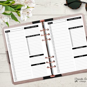 May include: Open planner with lined pages for daily scheduling. The pages are divided into sections for time slots, priorities, to-do lists, calls/emails, and notes. The planner is open on a light-colored surface with flowers and sunglasses.