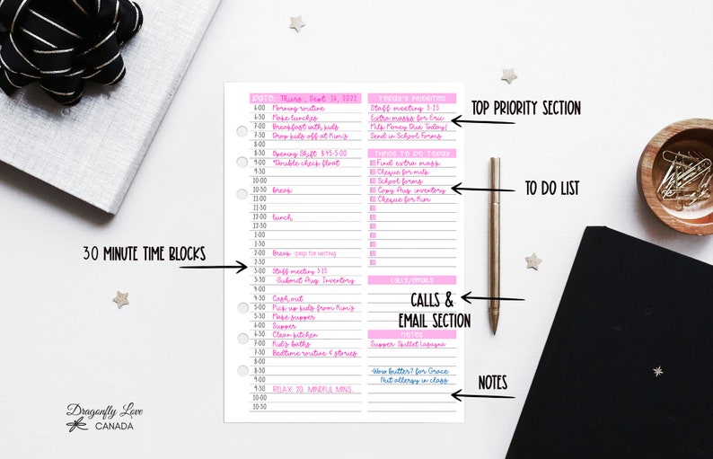 May include: A pink and white planner page with a detailed daily schedule, including time blocks, to-do lists, and notes. The page is surrounded by a pen, a wooden bowl with paper clips, and a black notebook. The planner has the text "Dragonfly Love Canada".