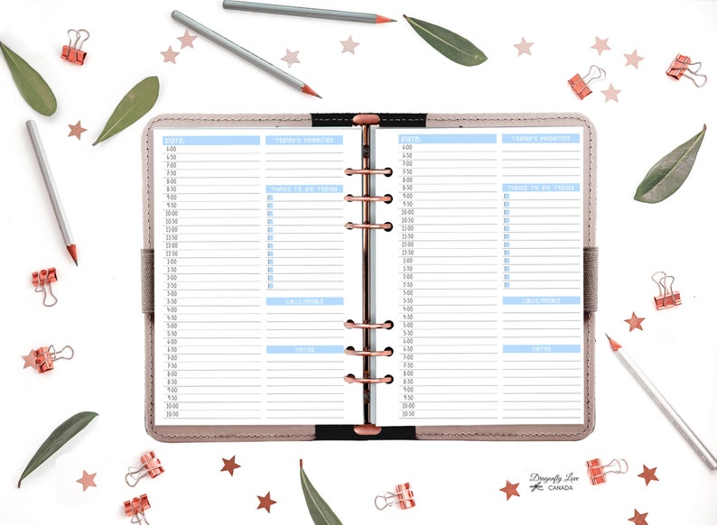 May include: Open planner with daily schedule pages. The pages have blue and white sections for time slots, priorities, and notes. The planner is surrounded by pencils, paper clips, leaves, and star-shaped confetti.