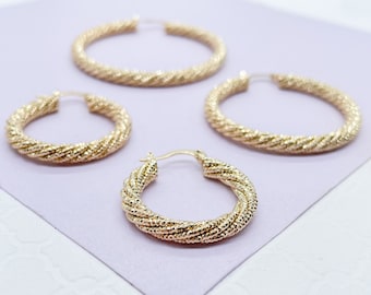 May include: Three gold hoop earrings of different sizes. The earrings are made of a twisted rope design with a textured surface.