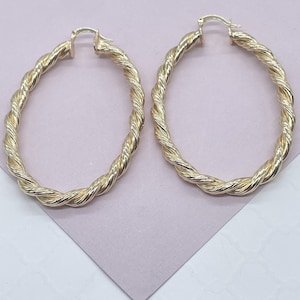 May include: A pair of gold-toned hoop earrings with a twisted rope design.