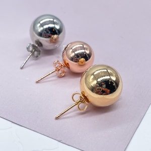 May include: Three pairs of stud earrings with round ball shapes. The earrings are silver, rose gold, and gold.