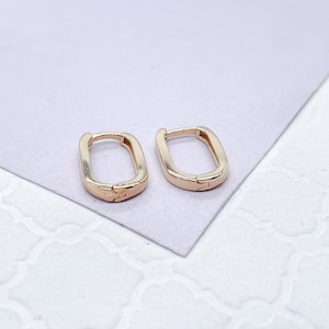 May include: A pair of gold hoop earrings with a rectangular shape. The earrings are made of a shiny metal and have a simple design.