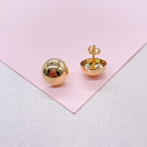 May include: A pair of gold ball stud earrings. The earrings are round and have a smooth, polished finish.