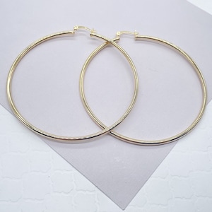 May include: A pair of large, gold hoop earrings. The hoops are thick and have a smooth finish.