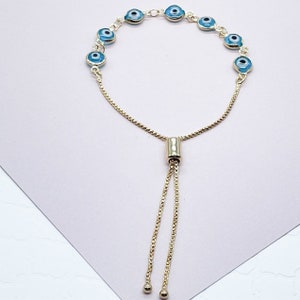 May include: A gold chain bracelet with blue evil eye charms. The bracelet has an adjustable sliding clasp.