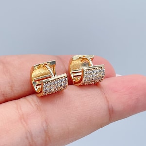 May include: A pair of gold hoop earrings with clear cubic zirconia stones. The earrings are small and delicate, and they would make a great gift for a friend or loved one.