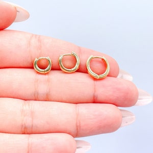 May include: Three gold hoop earrings of different sizes. The earrings are simple and elegant, and would make a great addition to any jewelry collection.