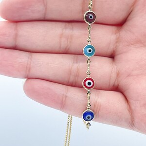 May include: A gold chain bracelet with five evil eye charms. The charms are blue, red, green, blue, and red. The evil eyes are all facing the same direction.