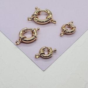 May include: Four gold-toned metal ring clasps of different sizes. The clasps are designed to be used for jewelry making.