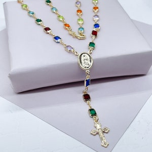 May include: A gold-toned rosary necklace with a colourful square bead design. The centrepiece features a gold oval pendant with a religious image. The necklace ends with a gold cross.