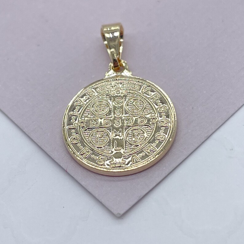 K&ouml;nnte beinhalten: Ein goldfarbener Anh&auml;nger mit einem detaillierten kreisf&ouml;rmigen Design. Der Anh&auml;nger hat oben eine Schlaufe f&uuml;r eine Kette und aufwendige gepr&auml;gte Muster und Text. Der Anh&auml;nger ist wahrscheinlich aus einem goldfarbenen Metall gefertigt.