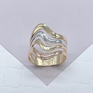 May include: A gold ring with three wavy bands in different shades of gold: yellow, white, and rose.