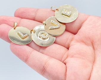Pode incluir: Quatro pingentes dourados com formato redondo e uma única letra no centro, cada letra é adornada com strass transparentes. As letras soletram a palavra "LOVE".