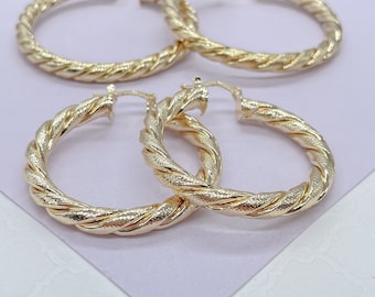 May include: Three gold hoop earrings with a twisted rope design. The earrings are made of a shiny metal and have a textured surface.
