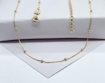 May include: A delicate gold chain necklace with small round beads. The chain is made of a fine, delicate metal and has a simple, elegant design.
