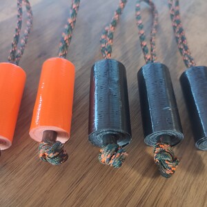 May include: Five rolls of tape, two orange and three black, with a camouflage cord attached to each roll.