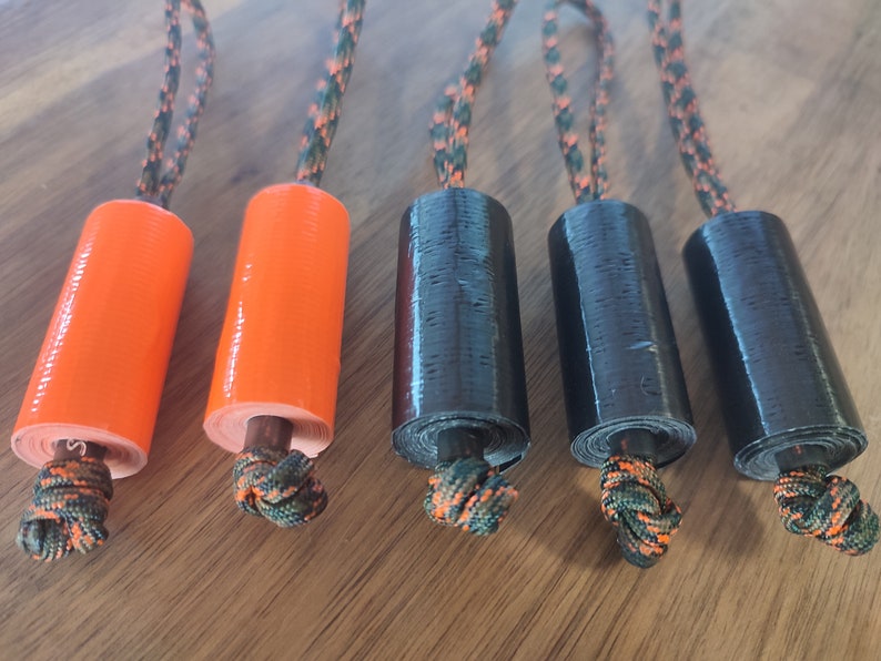 May include: Five rolls of tape, two orange and three black, with a camouflage cord attached to each roll.