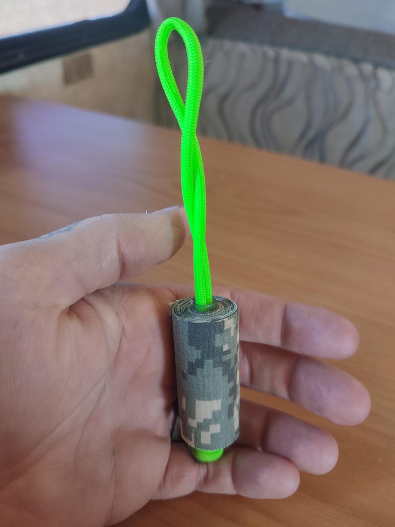 May include: A green rope with a camouflage fabric wrapped around it. The rope is tied in a loop at the top.