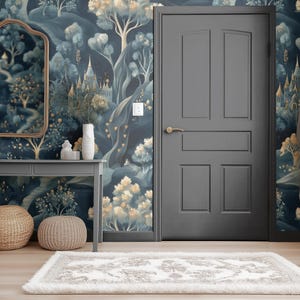 May include: A room with a whimsical mural featuring castles and trees in shades of blue, gold, and green. A gray door, table, and mirror frame complement the wallpaper. Two woven ottomans and a rug complete the decor.