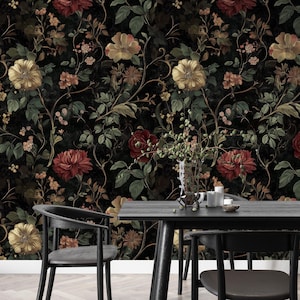 Puede incluir: Un papel tapiz floral en blanco y negro con una est&eacute;tica vintage oscura. El papel tapiz presenta un patr&oacute;n repetitivo de flores y hojas rojas, amarillas y verdes. El papel tapiz se muestra en un ambiente de comedor con una mesa y sillas negras.