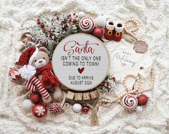 Könnte beinhalten: Eine Baby-Ankündigung im Weihnachts-Design mit einem runden Schild, auf dem steht: "Der Weihnachtsmann ist nicht der Einzige, der in die Stadt kommt! Ankunft im August 2024". Das Schild ist umgeben von roten und weißen Ornamenten, einem Teddybär und einem Baby-Strampler mit dem Namen "McKinney" darauf.