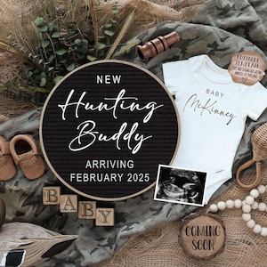 Puede incluir: Un tablero de letras blanco y negro con el texto "New Hunting Buddy Arriving February 2025". Un body blanco con el texto "Baby McKinney" está al lado del tablero de letras. Un letrero de madera con el texto "Coming Soon" está en la parte inferior derecha de la imagen. También hay bloques de madera que deletrean "Baby" y un sonajero de bebé marrón y blanco.