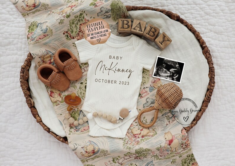 May include: A white baby onesie with the text "Baby McKinney October 2023" on it. The onesie is laid out in a wicker basket with a Winnie the Pooh themed blanket, brown baby shoes, a wooden baby rattle, a pacifier, and a framed ultrasound image.